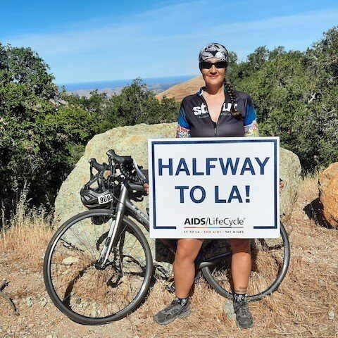 A man holding up a sign next to his bike.