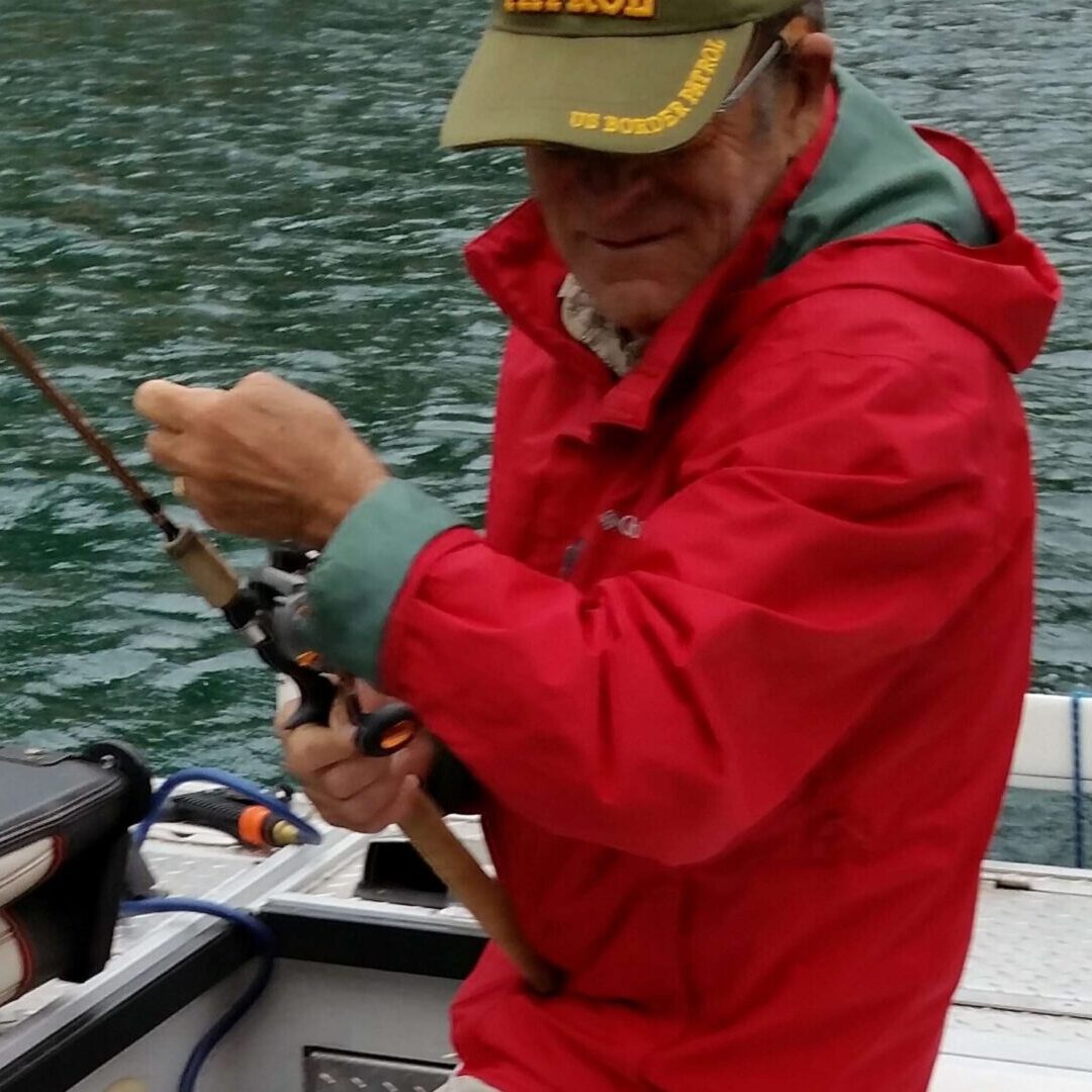 A man in red jacket holding fishing rod on boat.