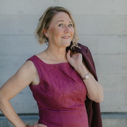 A woman in a pink dress holding her jacket.